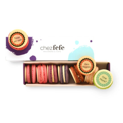 Стилна кутия Chez Fefe със седем френски макарона, декорирани с шоколадови медальони с надписи "Treat yo' self", "Zero Regrets", "One More?" и други забавни фрази.